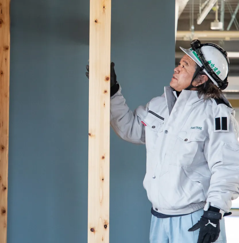 建築中の屋内で木の柱の設置状況を確認するY・Aさん