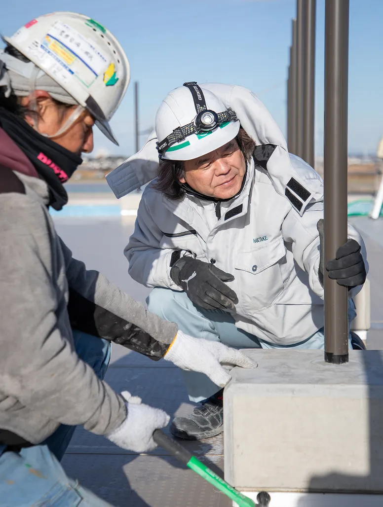 屋外で基礎部分の仕上げ作業を真剣な表情で行うY・Aさん