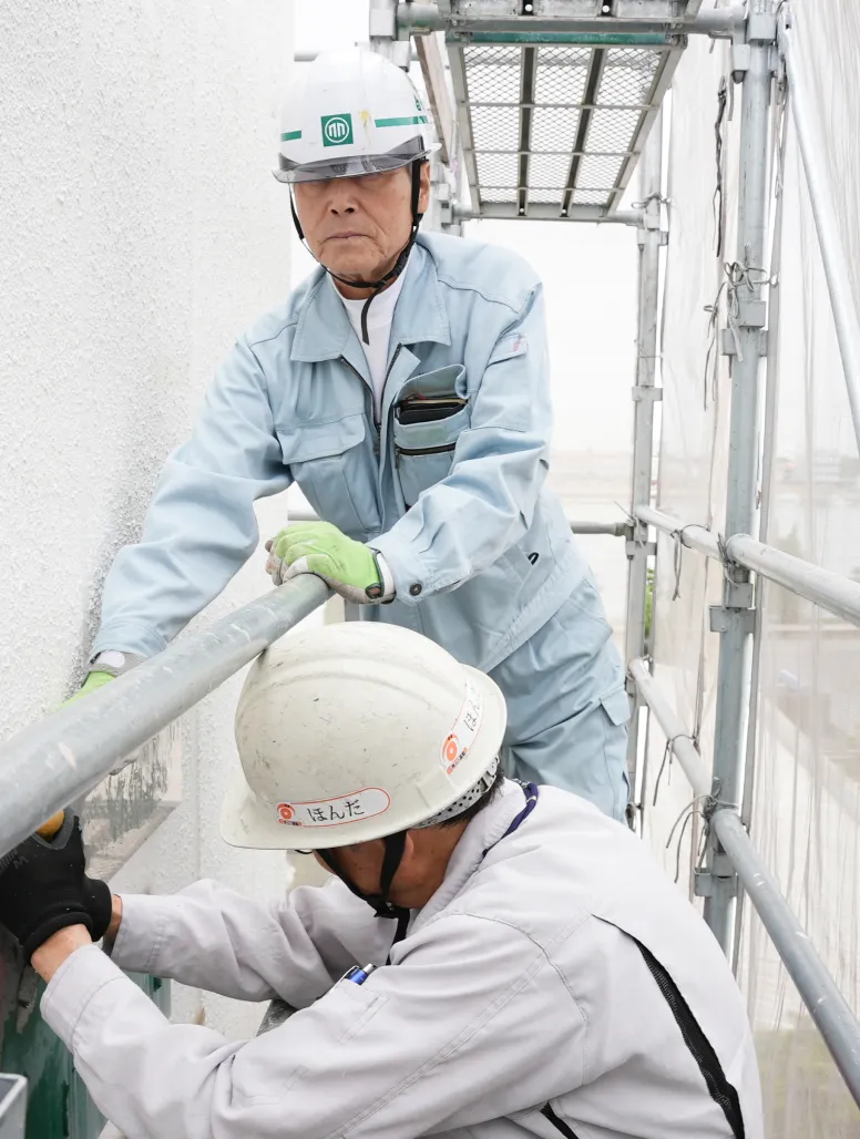足場の上で資材の組み立て作業を真剣な表情で行うS・Sさん